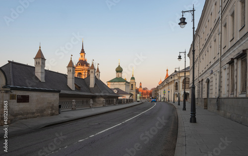 Moscow street in the early morning. The road is without cars. Ancient houses and churches. Red square in the background. Clear sky