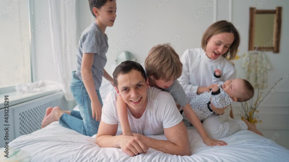 Family with three kids having fun in bed. Happy family concept. Father's day. High quality 4k footage Family with three kids having fun in bed. Happy family concept. Father's day. High quality 4k footage