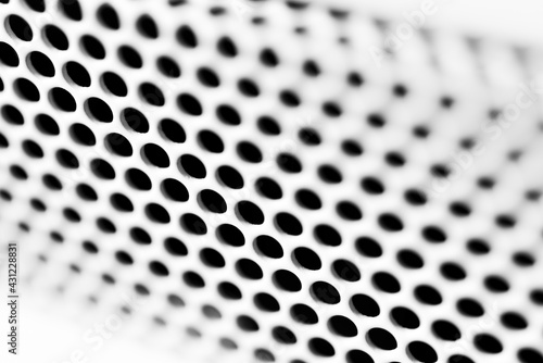 White ventilation grille. Round holes. Metal construction. Dark background. Close-up view. Black and white tones. © Georgii Shipin