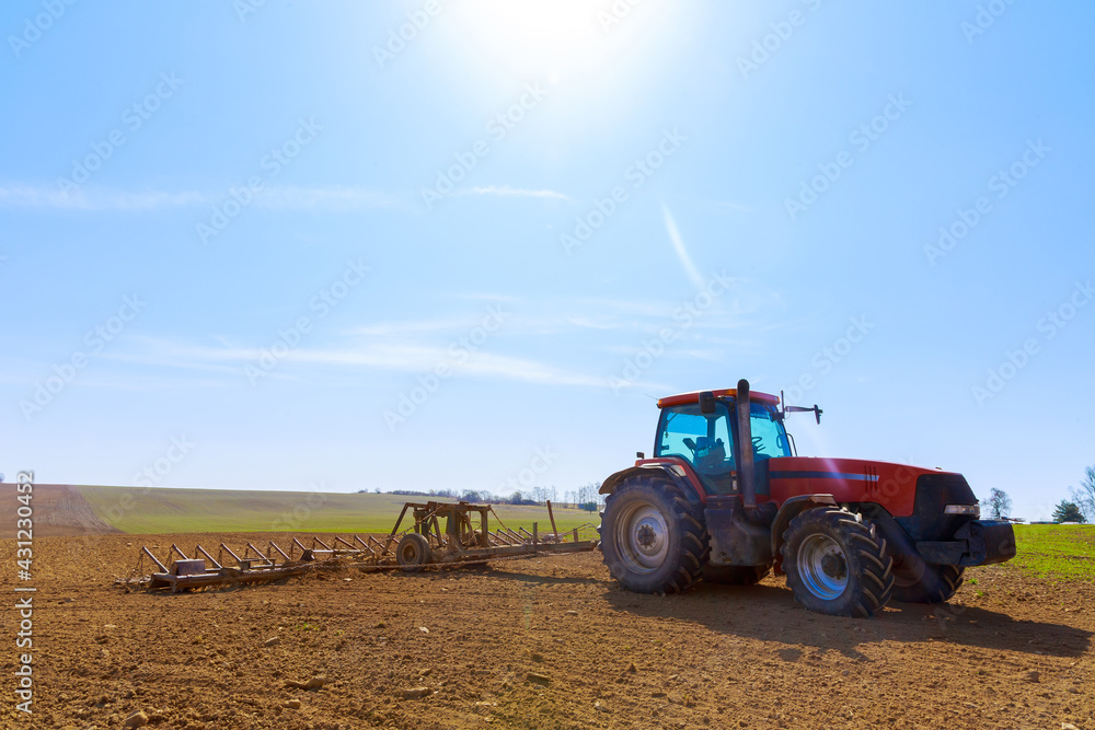 A farmer plows the soil in the field with a chisel plow on a tractor. Agricultural tractor with a plow on farmland. A farmer plows the soil in the field with a chisel plow on a tractor. Agricultural tractor with a plow on farmland.