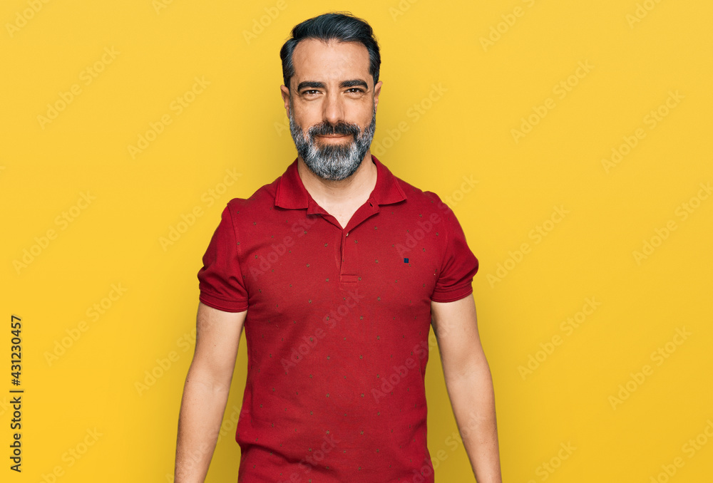 Middle aged man with beard wearing casual red t shirt looking positive and happy standing and smiling with a confident smile showing teeth Middle aged man with beard wearing casual red t shirt looking positive and happy standing and smiling with a confident smile showing teeth