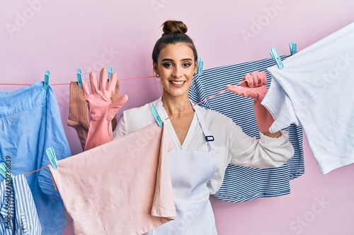 Beautiful brunette young woman washing clothes at clothesline showing and pointing up with fingers number six while smiling confident and happy.