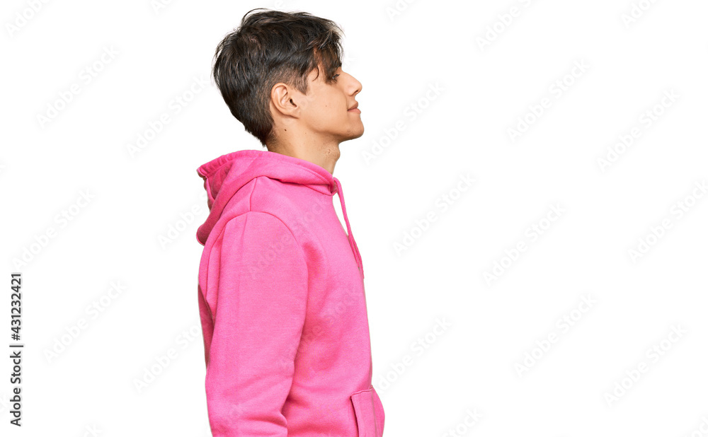Young hispanic man wearing casual pink sweatshirt looking to side, relax profile pose with natural face with confident smile.
