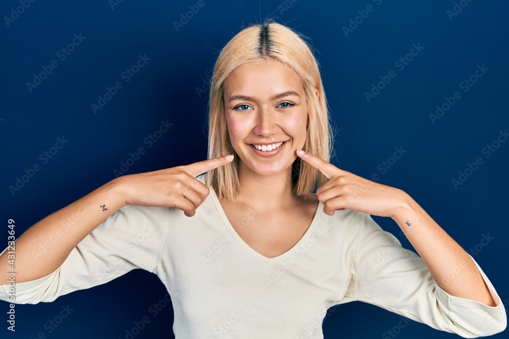 Beautiful blonde woman wearing casual sweater smiling cheerful showing and pointing with fingers teeth and mouth. dental health concept. Beautiful blonde woman wearing casual sweater smiling cheerful showing and pointing with fingers teeth and mouth. dental health concept.