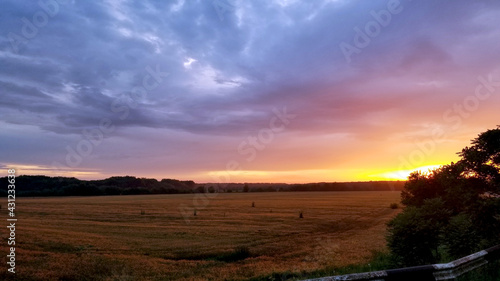 beautiful violet-orange sunset over a mown wheat field  the sky is covered with clouds