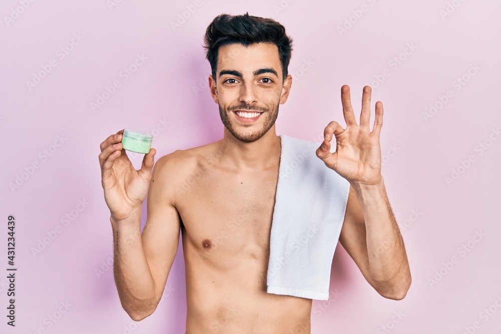 Young hispanic man shirtless wearing towel and eye bags patches doing ok sign with fingers, smiling friendly gesturing excellent symbol Young hispanic man shirtless wearing towel and eye bags patches doing ok sign with fingers, smiling friendly gesturing excellent symbol