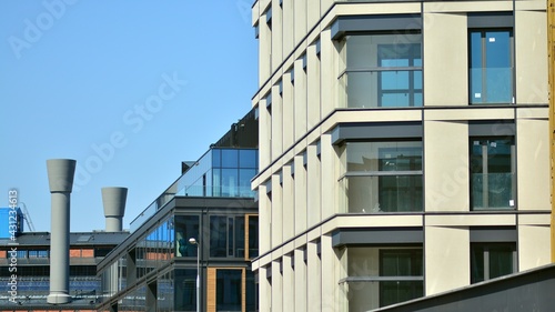 A residential building and an adjacent office building. Modern urban development. Buildings against blue sky and sun light. 