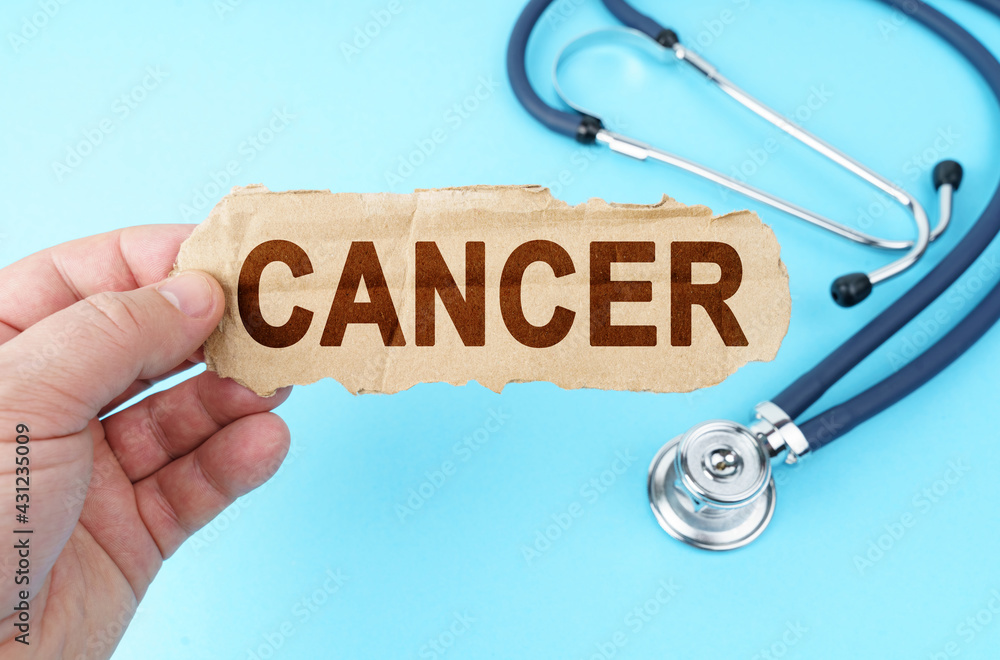 On a blue background, a man holds a cardboard box with the inscription - CANCER On a blue background, a man holds a cardboard box with the inscription - CANCER