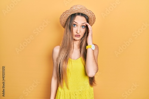 Young blonde girl wearing summer hat worried and stressed about a problem with hand on forehead, nervous and anxious for crisis