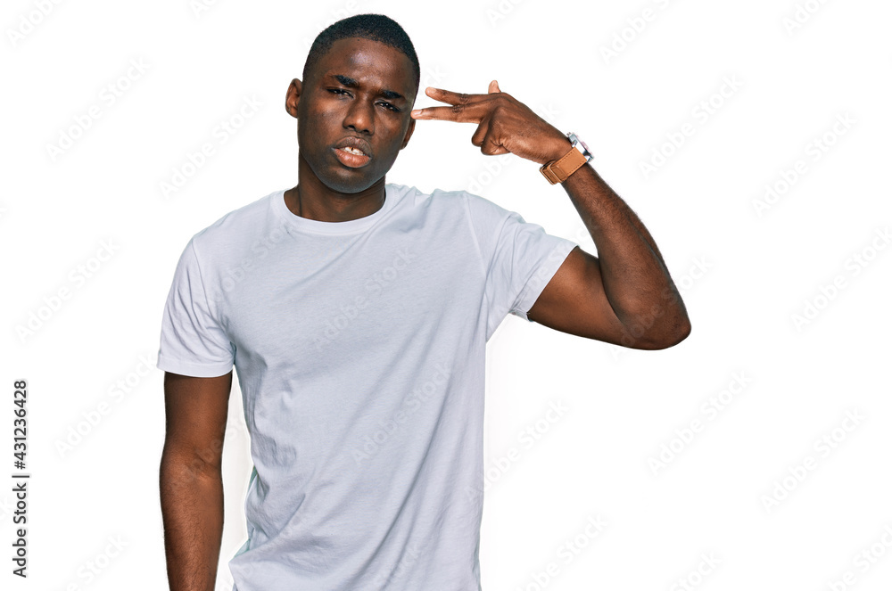 Young african american man wearing casual white t shirt shooting and killing oneself pointing hand and fingers to head like gun, suicide gesture. Young african american man wearing casual white t shirt shooting and killing oneself pointing hand and fingers to head like gun, suicide gesture.