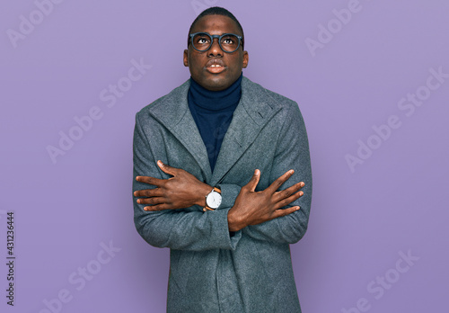 Young african american man wearing business clothes and glasses shaking and freezing for winter cold with sad and shock expression on face