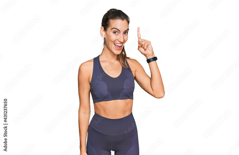 Young beautiful woman wearing sportswear pointing finger up with successful idea. exited and happy. number one. Young beautiful woman wearing sportswear pointing finger up with successful idea. exited and happy. number one.