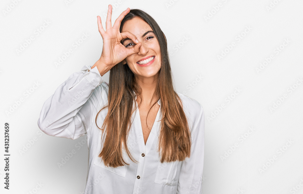 Young beautiful woman wearing casual clothes doing ok gesture with hand smiling, eye looking through fingers with happy face. Young beautiful woman wearing casual clothes doing ok gesture with hand smiling, eye looking through fingers with happy face.