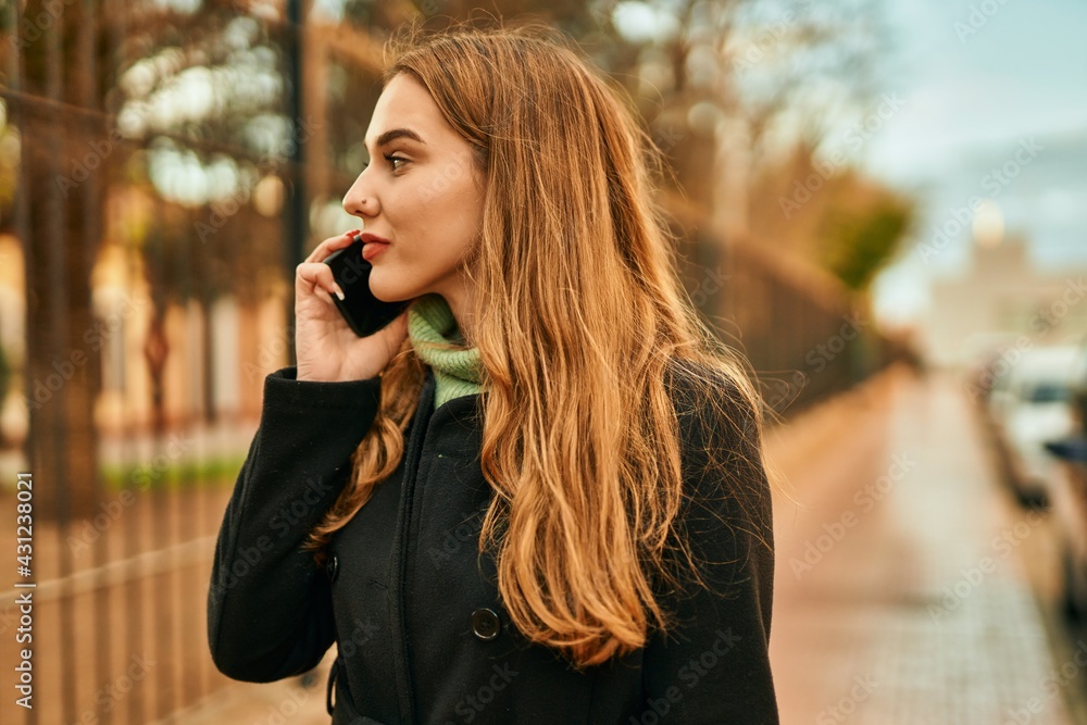 Young blonde girl smiling happy talking on the smartphone at the city. Young blonde girl smiling happy talking on the smartphone at the city.