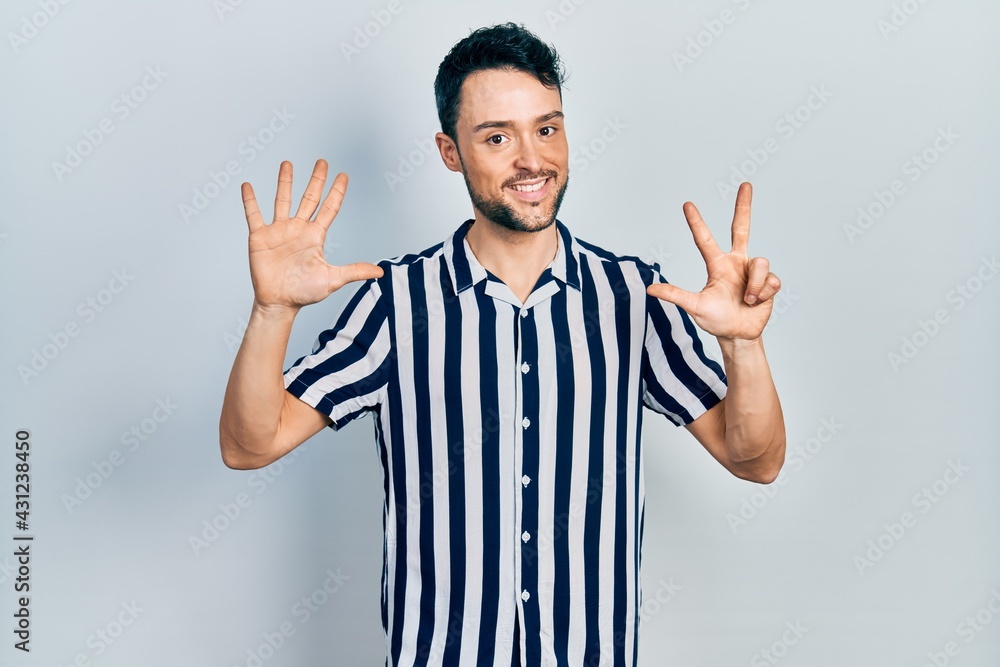 Young hispanic man wearing casual clothes showing and pointing up with fingers number eight while smiling confident and happy. Young hispanic man wearing casual clothes showing and pointing up with fingers number eight while smiling confident and happy.