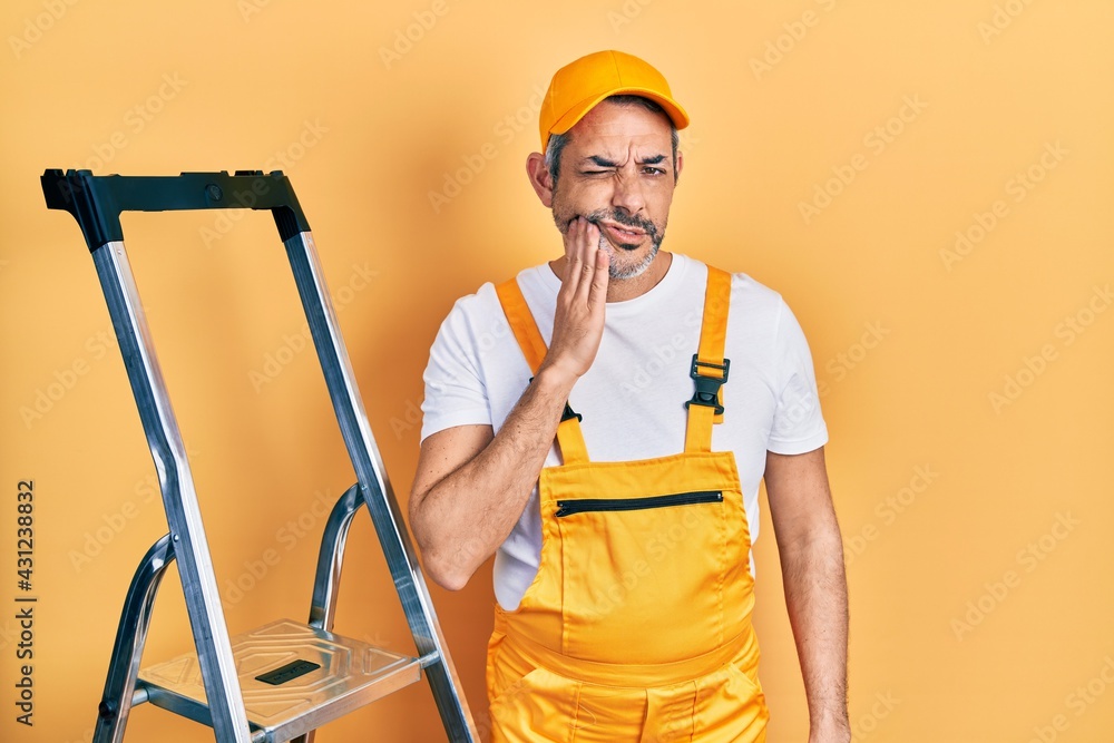 Handsome middle age man with grey hair holding ladder touching mouth with hand with painful expression because of toothache or dental illness on teeth. dentist Handsome middle age man with grey hair holding ladder touching mouth with hand with painful expression because of toothache or dental illness on teeth. dentist
