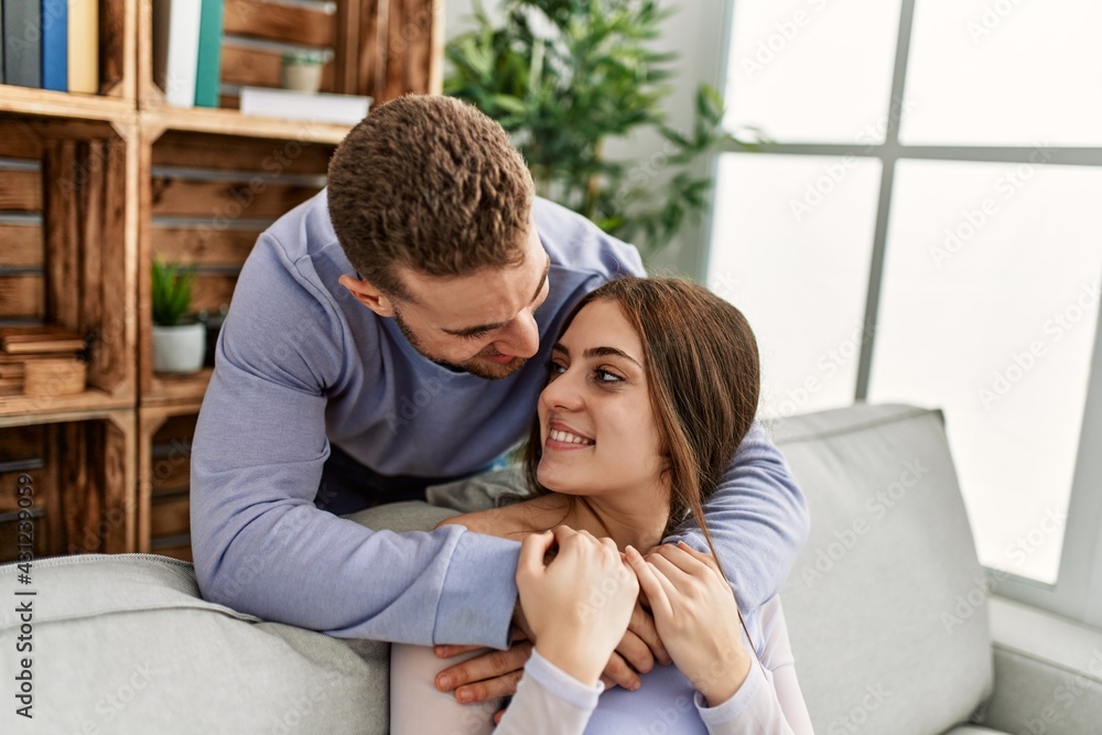 Young caucasian couple sitting on the sofa hugging at home. Young caucasian couple sitting on the sofa hugging at home.