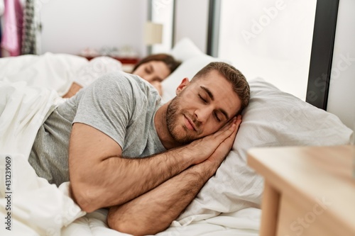 Young caucasian couple sleeping on bed at home.