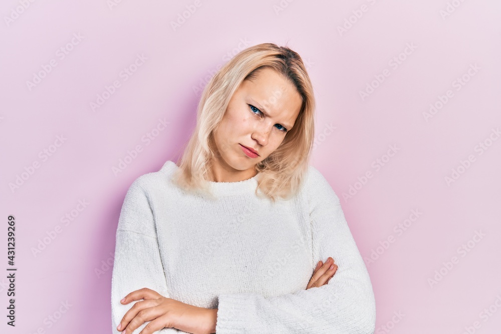 Beautiful caucasian blonde woman wearing casual winter sweater skeptic and nervous, disapproving expression on face with crossed arms. negative person. Beautiful caucasian blonde woman wearing casual winter sweater skeptic and nervous, disapproving expression on face with crossed arms. negative person.