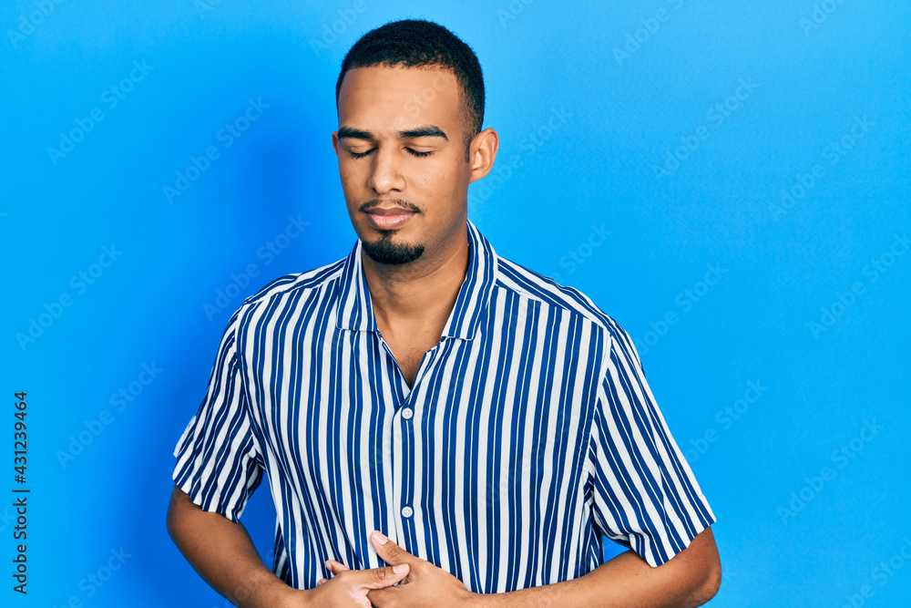 Young african american man wearing casual clothes with hand on stomach because indigestion, painful illness feeling unwell. ache concept. Young african american man wearing casual clothes with hand on stomach because indigestion, painful illness feeling unwell. ache concept.