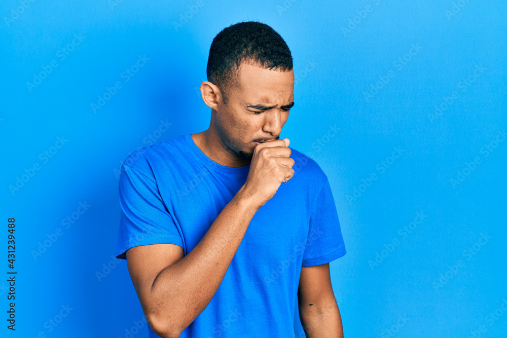 Young african american man wearing casual blue t shirt feeling unwell and coughing as symptom for cold or bronchitis. health care concept. Young african american man wearing casual blue t shirt feeling unwell and coughing as symptom for cold or bronchitis. health care concept.
