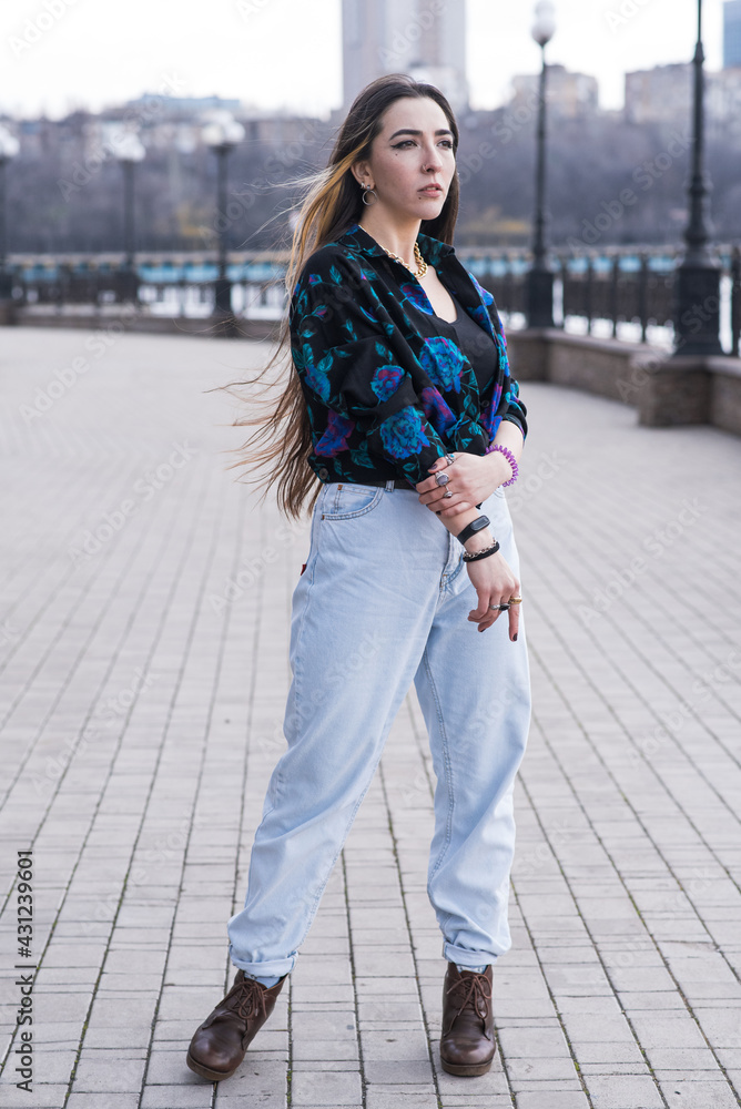 Fototapeta premium Portrait of a stylish and beautiful hippie girl in the park in cloudy weather