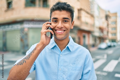 Young latin man smiling happy talking on the smartphone walking at the city.