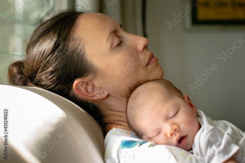 Tired exhausted mother taking a nap with her baby at home. Motherhood and maternity. photo