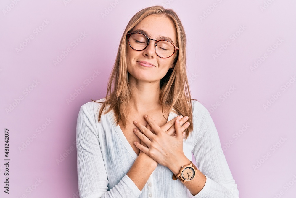 Beautiful blonde woman wearing casual clothes and glasses smiling with hands on chest, eyes closed with grateful gesture on face. health concept. Beautiful blonde woman wearing casual clothes and glasses smiling with hands on chest, eyes closed with grateful gesture on face. health concept.