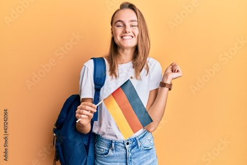 Beautiful blonde woman exchange student holding germany flag screaming proud  celebrating victory and success very excited with raised arm