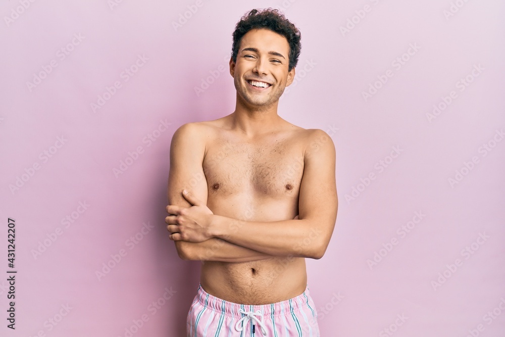 Fototapeta premium Young handsome man wearing swimwear shirtless happy face smiling with crossed arms looking at the camera. positive person.