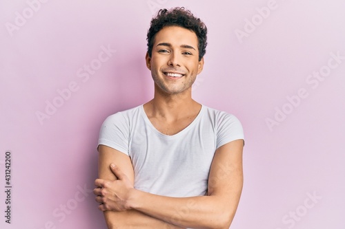 Young handsome man wearing casual white t shirt happy face smiling with crossed arms looking at the camera. positive person. photo