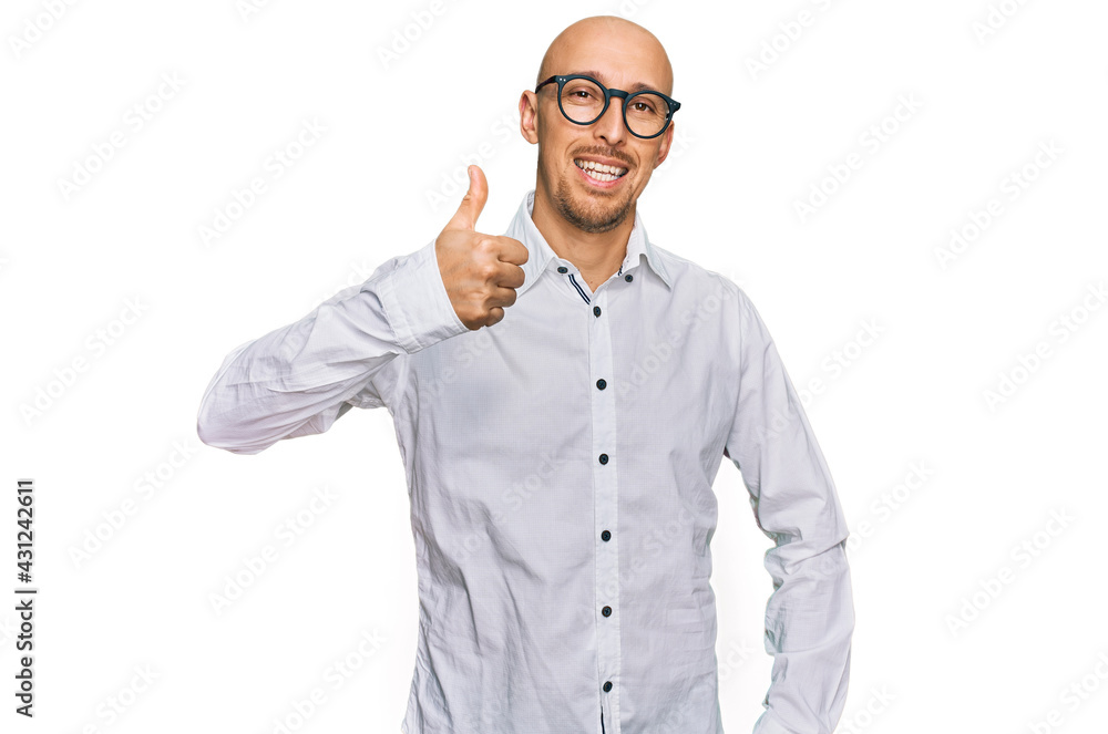 Bald man with beard wearing business shirt and glasses doing happy thumbs up gesture with hand. approving expression looking at the camera showing success. Bald man with beard wearing business shirt and glasses doing happy thumbs up gesture with hand. approving expression looking at the camera showing success.