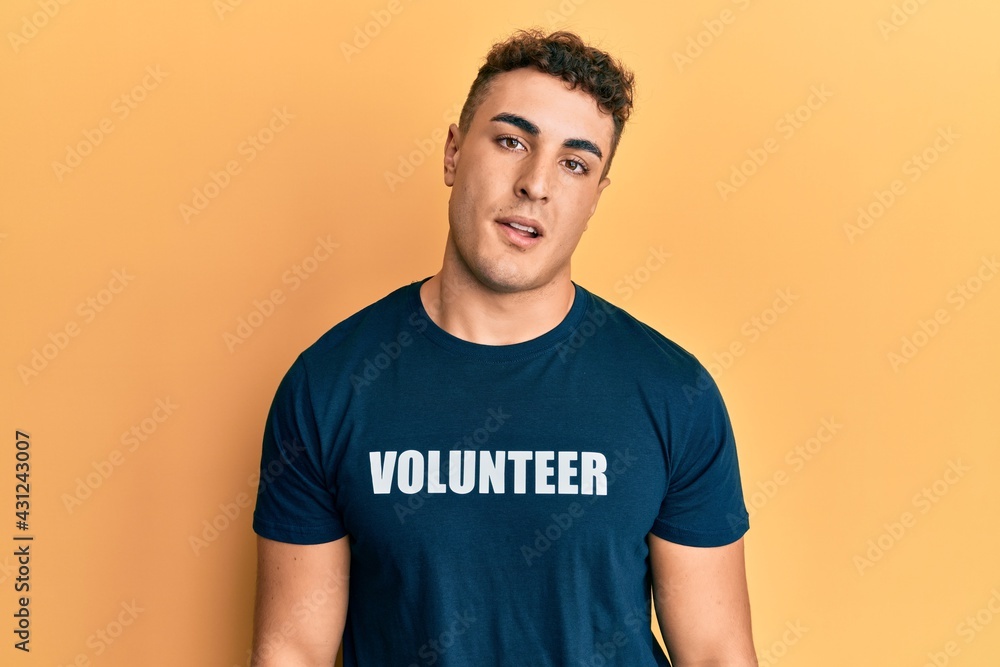 Hispanic young man wearing volunteer t shirt looking sleepy and tired, exhausted for fatigue and hangover, lazy eyes in the morning. Hispanic young man wearing volunteer t shirt looking sleepy and tired, exhausted for fatigue and hangover, lazy eyes in the morning.