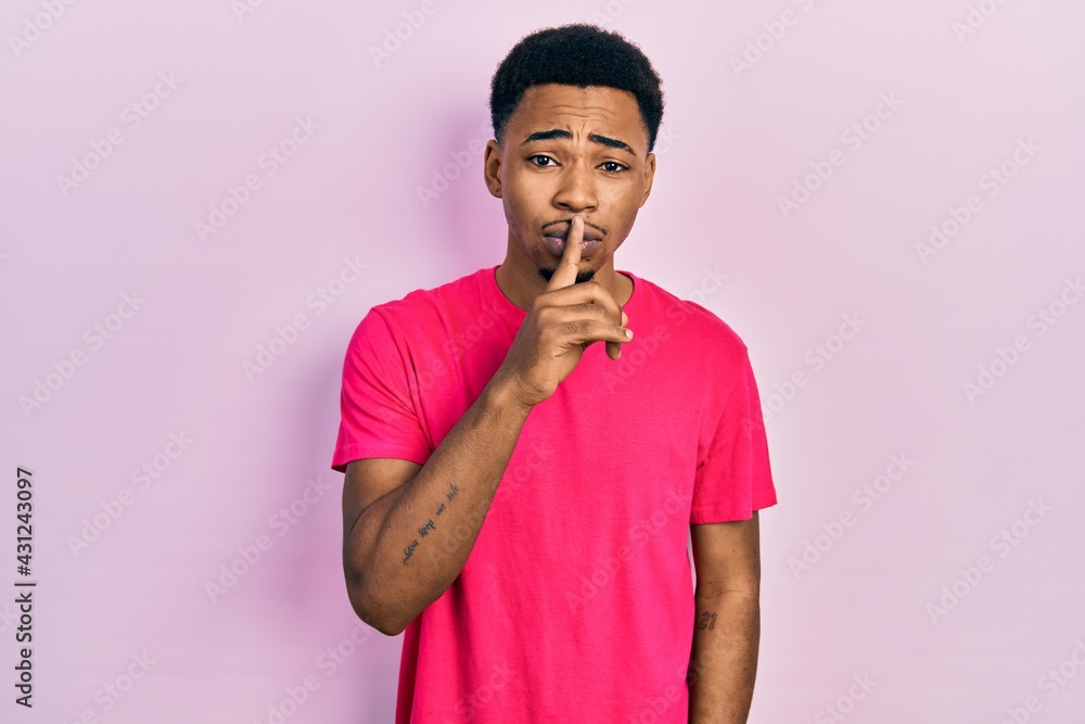 Young african american man wearing casua t shirt asking to be quiet with finger on lips. silence and secret concept. Young african american man wearing casua t shirt asking to be quiet with finger on lips. silence and secret concept.