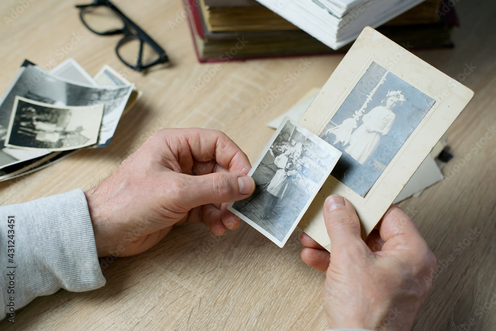 Obraz na płótnie closeup male hand holding old vintage photos of 1940-1950, concept of family tree, genealogy, childhood memories, memory of ancestors w salonie