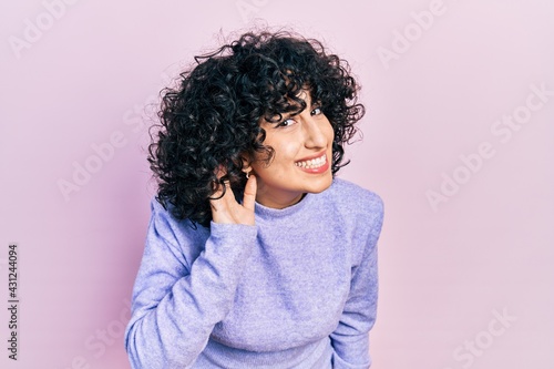 Young middle east woman wearing casual clothes smiling with hand over ear listening an hearing to rumor or gossip. deafness concept.
