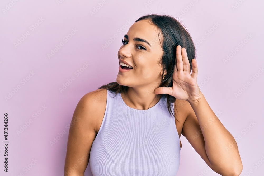 Young brunette woman wearing casual clothes smiling with hand over ear listening and hearing to rumor or gossip. deafness concept. Young brunette woman wearing casual clothes smiling with hand over ear listening and hearing to rumor or gossip. deafness concept.
