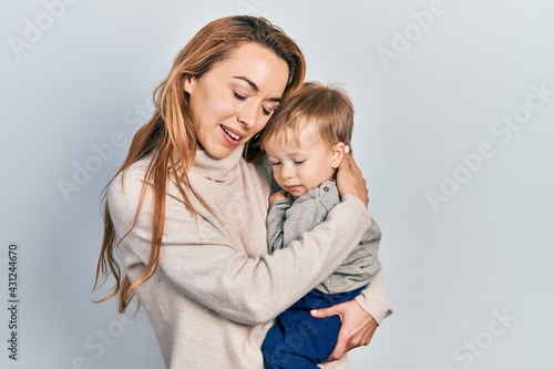 Young caucasian woman holding and hugging her son with love. Family of two bonding together. Mother holding infant toddler