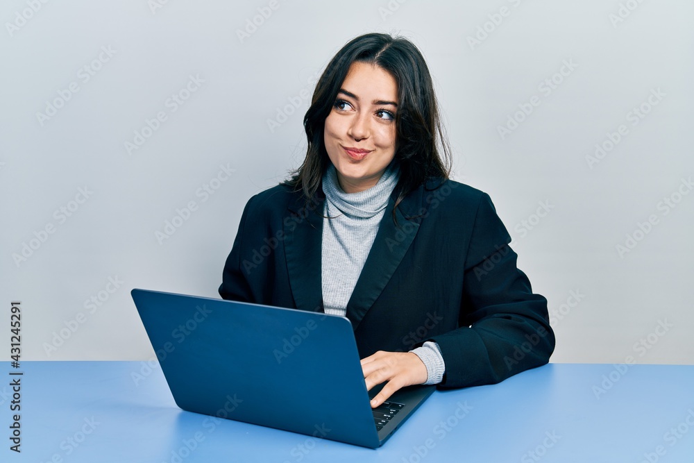 Beautiful hispanic woman working at the office with laptop smiling looking to the side and staring away thinking. Beautiful hispanic woman working at the office with laptop smiling looking to the side and staring away thinking.