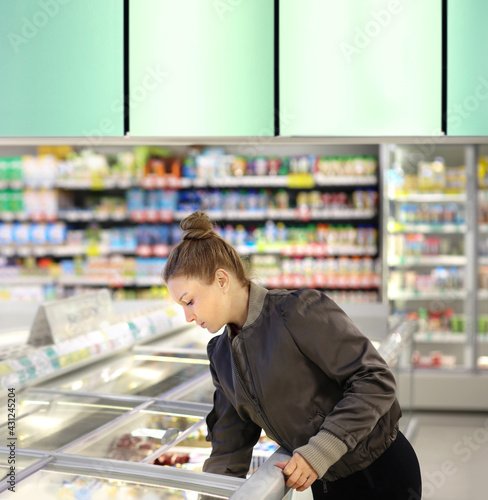 Woman choosing frozen food from a supermarket freezer