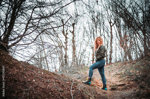 Portrait of young woman with curly hair standing on the hill. Copy space