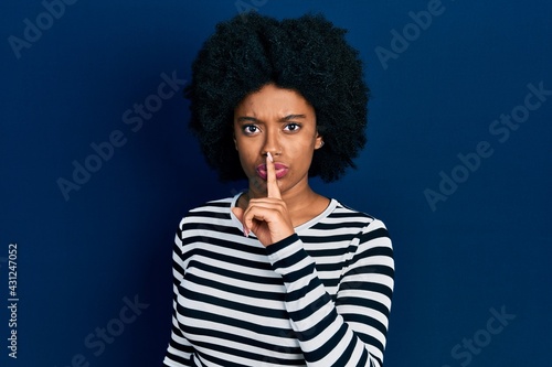 Young african american woman wearing casual clothes asking to be quiet with finger on lips. silence and secret concept.
