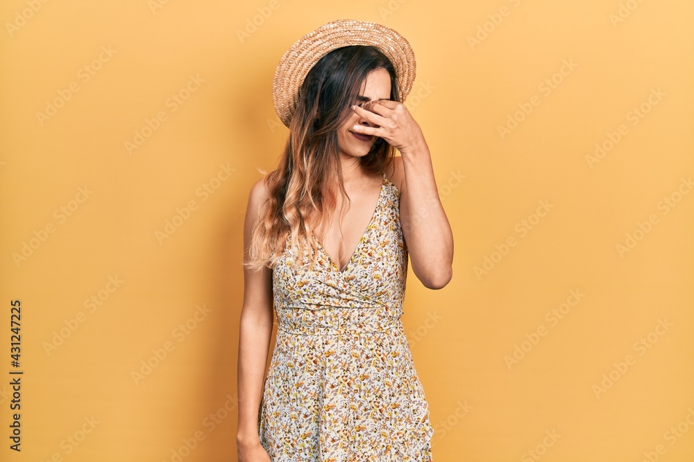 Young hispanic girl wearing summer hat tired rubbing nose and eyes feeling fatigue and headache. stress and frustration concept. Young hispanic girl wearing summer hat tired rubbing nose and eyes feeling fatigue and headache. stress and frustration concept.