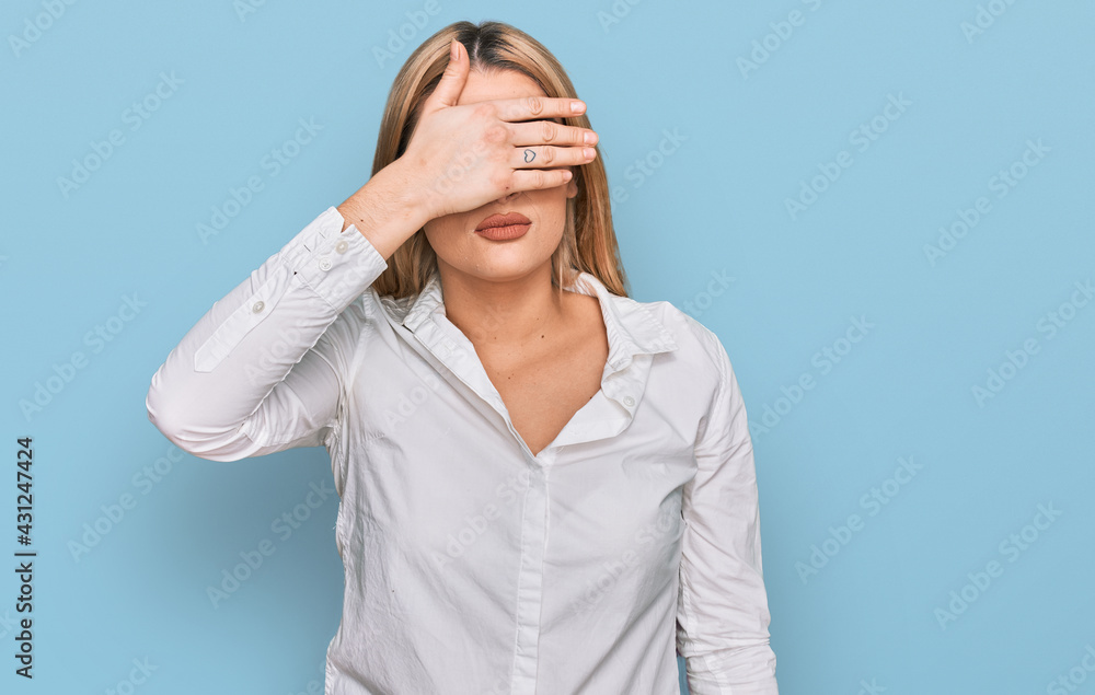 Young caucasian woman wearing casual clothes covering eyes with hand, looking serious and sad. sightless, hiding and rejection concept Young caucasian woman wearing casual clothes covering eyes with hand, looking serious and sad. sightless, hiding and rejection concept
