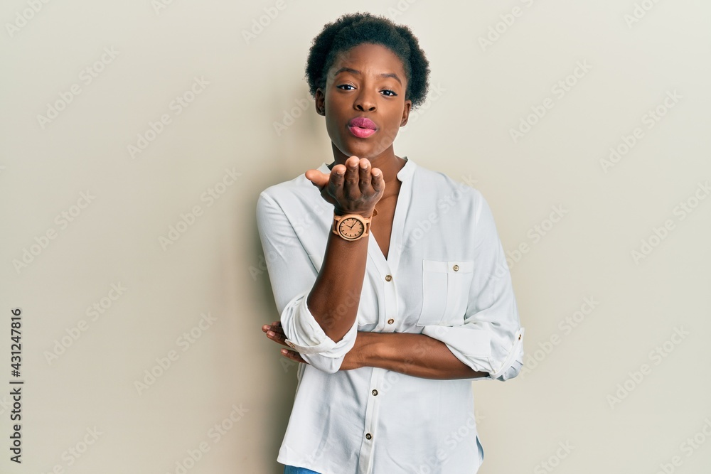 Young african american girl wearing casual clothes looking at the camera blowing a kiss with hand on air being lovely and sexy. love expression. Young african american girl wearing casual clothes looking at the camera blowing a kiss with hand on air being lovely and sexy. love expression.