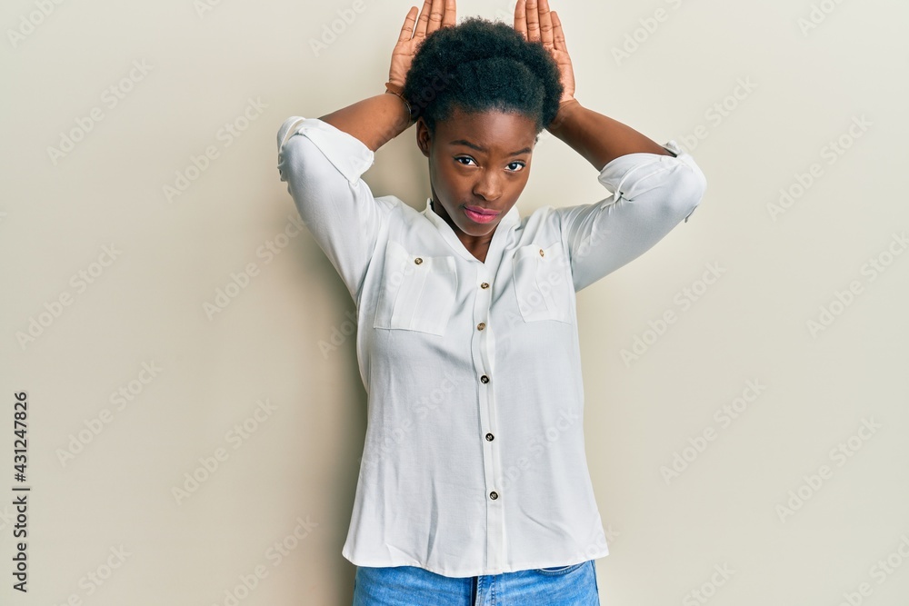 Young african american girl wearing casual clothes doing bunny ears gesture with hands palms looking cynical and skeptical. easter rabbit concept. Young african american girl wearing casual clothes doing bunny ears gesture with hands palms looking cynical and skeptical. easter rabbit concept.
