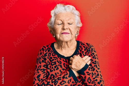 Senior grey-haired woman wearing casual clothes smiling with hands on chest, eyes closed with grateful gesture on face. health concept.
