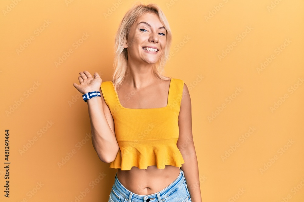 Young blonde girl wearing casual clothes waiving saying hello happy and smiling, friendly welcome gesture Young blonde girl wearing casual clothes waiving saying hello happy and smiling, friendly welcome gesture