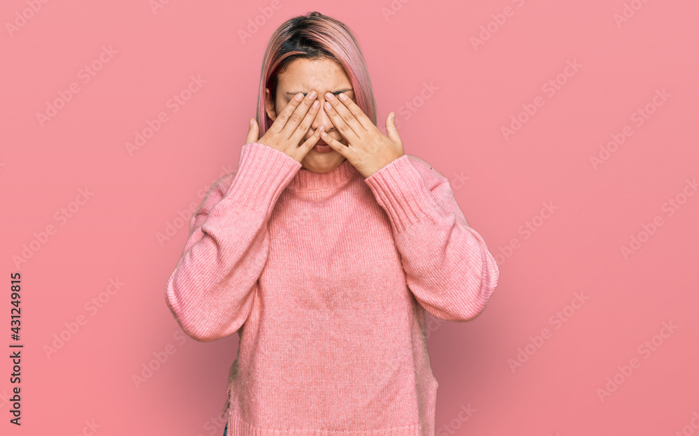 Hispanic woman with pink hair wearing casual winter sweater rubbing eyes for fatigue and headache, sleepy and tired expression. vision problem Hispanic woman with pink hair wearing casual winter sweater rubbing eyes for fatigue and headache, sleepy and tired expression. vision problem